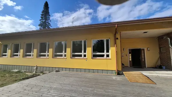 Manskiven asumisyksikkö ulkoa — keltainen rakennus, sisäänkäyntiluiska ja puinen terassi