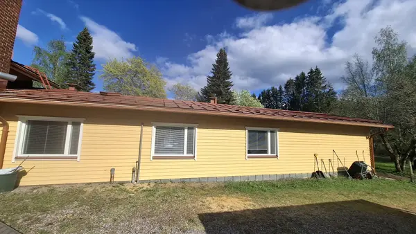 Manskiven rakennus sivusta — ympärillä puutarha ja luonto