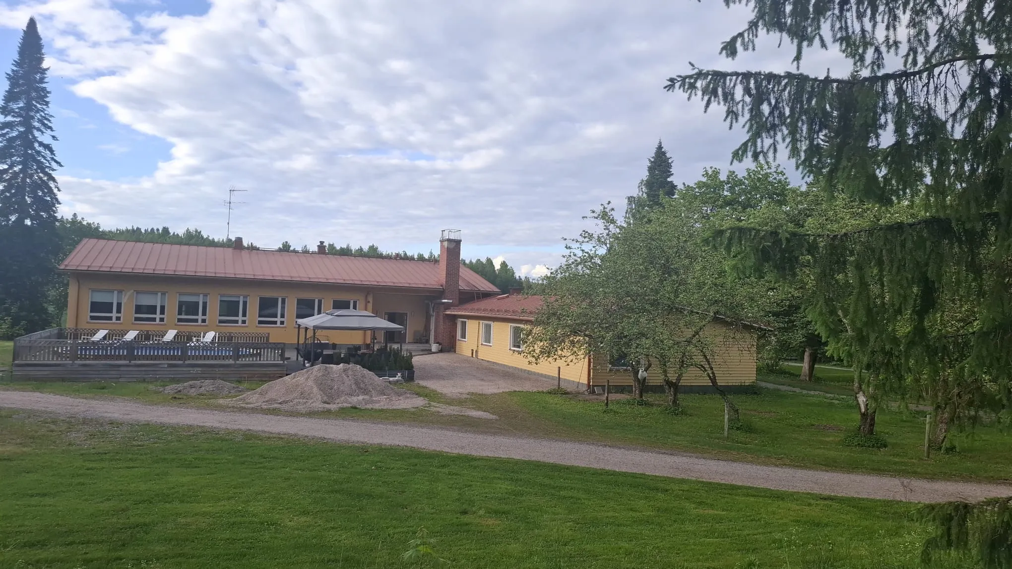 Manskiven asumisyksikkö ulkoa — koko rakennuksen julkisivu, piha ja kesäinen ympäristö