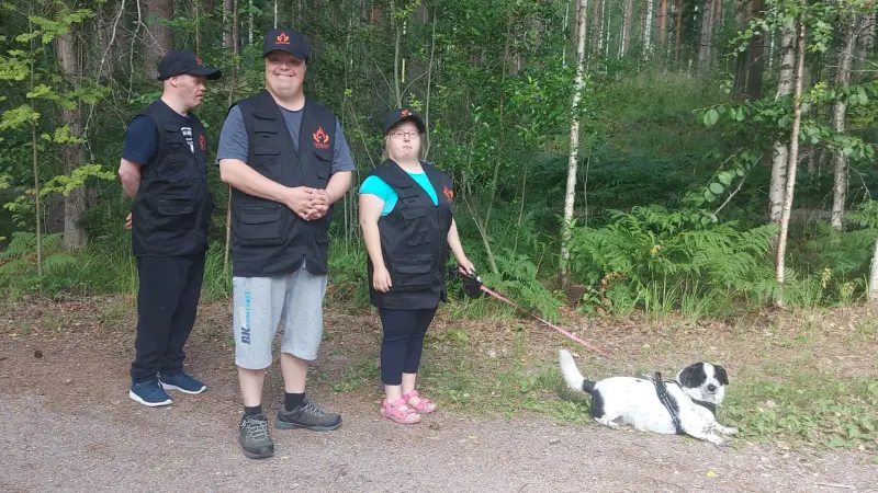 Päivätoimintalainen kävelee metsässä koiran kanssa